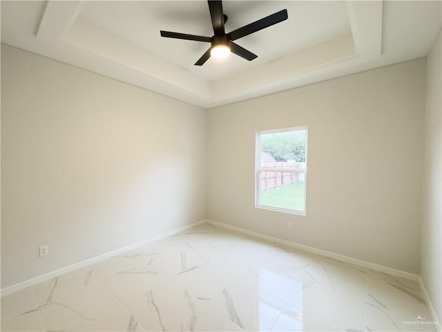 empty room featuring ceiling fan and a raised ceiling