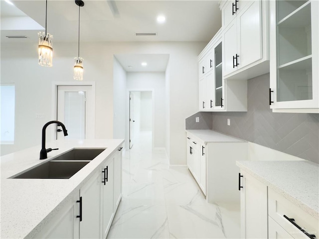 kitchen with sink, decorative backsplash, light stone countertops, and white cabinets