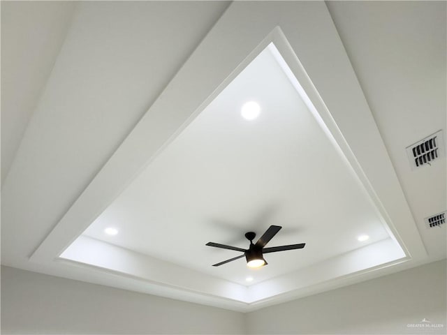 interior details with ceiling fan and a raised ceiling