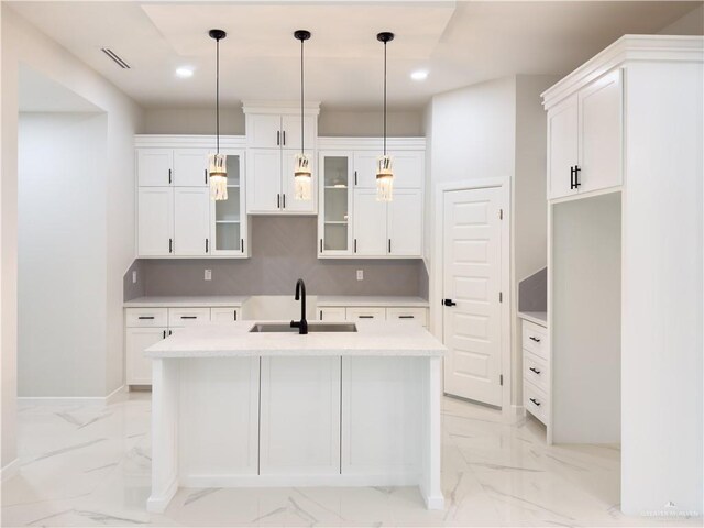 kitchen featuring pendant lighting, sink, a center island with sink, and white cabinets