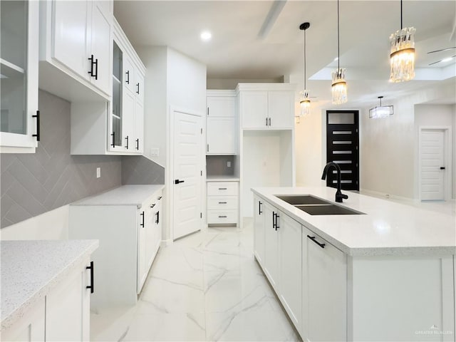 kitchen with decorative light fixtures, sink, decorative backsplash, and white cabinets