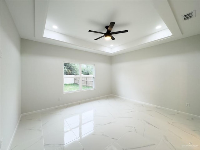 spare room featuring ceiling fan and a tray ceiling