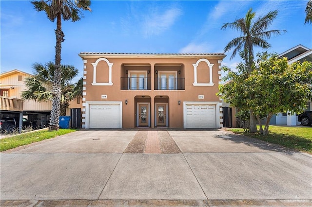 mediterranean / spanish house with stucco siding, an attached garage, a balcony, and driveway