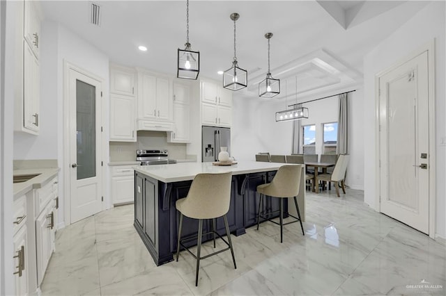 kitchen featuring white cabinetry, a kitchen island, hanging light fixtures, and appliances with stainless steel finishes