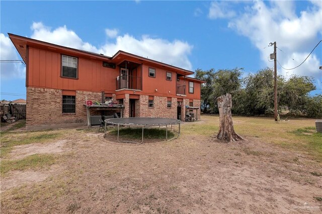 back of property featuring a balcony and a trampoline