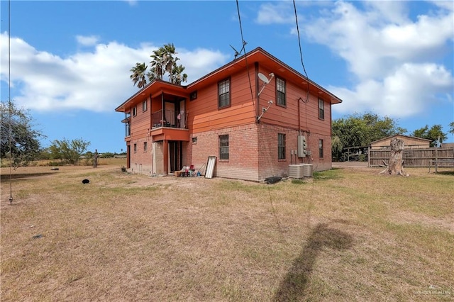 rear view of property featuring a lawn and a balcony