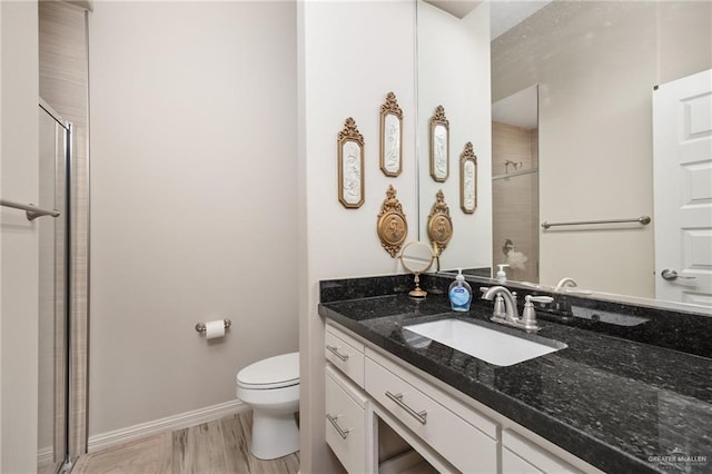 bathroom featuring a shower with shower door, vanity, wood-type flooring, and toilet