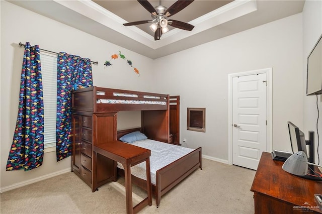 bedroom featuring ceiling fan, light colored carpet, crown molding, and a tray ceiling