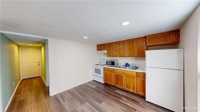 kitchen featuring white appliances, sink, and hardwood / wood-style floors