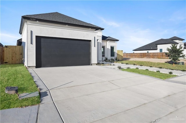 view of front of home with driveway, an attached garage, fence, and stucco siding