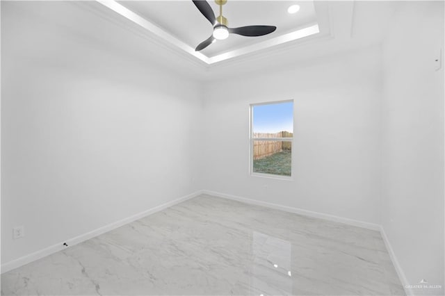 unfurnished room with marble finish floor, a tray ceiling, a ceiling fan, and baseboards