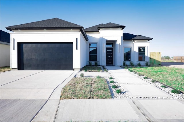 prairie-style house featuring a garage, driveway, a shingled roof, and stucco siding