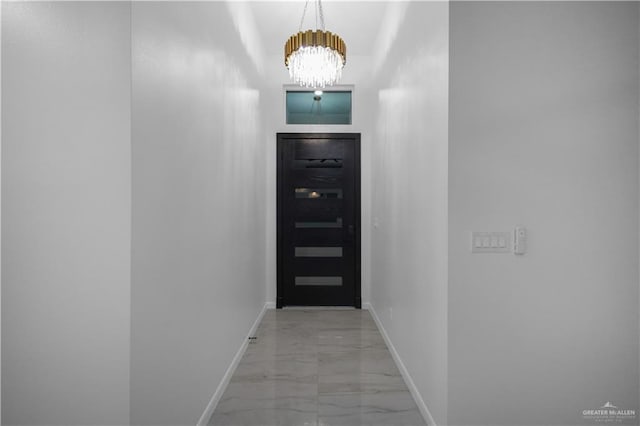 doorway featuring a chandelier, marble finish floor, and baseboards