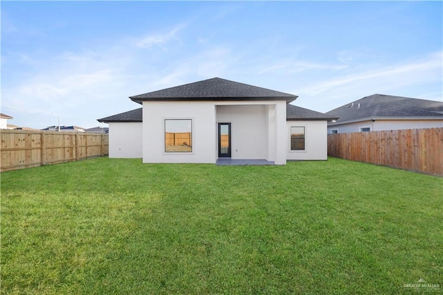 back of house with a yard, a fenced backyard, and stucco siding