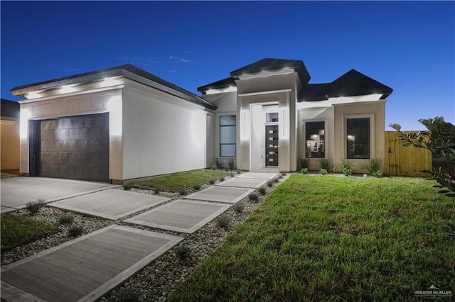 view of front of property with a garage, concrete driveway, fence, a front yard, and stucco siding