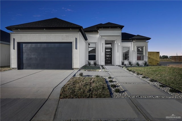 prairie-style house featuring a garage, concrete driveway, and stucco siding