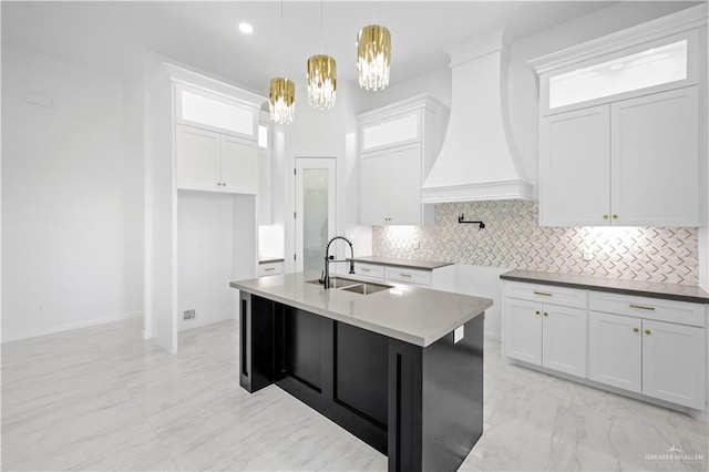 kitchen with marble finish floor, premium range hood, tasteful backsplash, and a sink