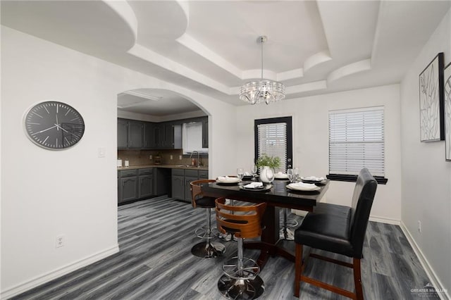 2715 Melanie Dr, Pharr, TX 78577 - dining space with baseboards, a chandelier, dark wood-type flooring, a raised ceiling, and arched walkways