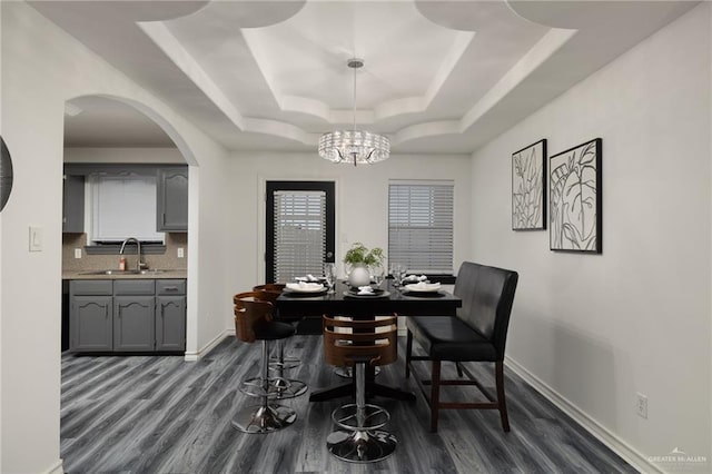 2715 Melanie Dr, Pharr, TX 78577 - dining room featuring baseboards, a raised ceiling, arched walkways, a notable chandelier, and dark wood finished floors