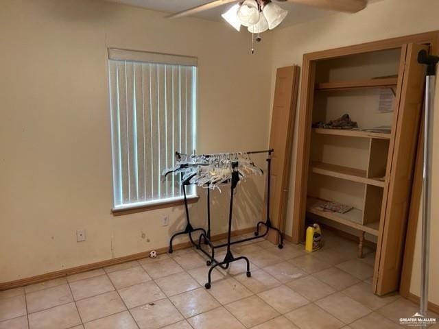 interior space featuring light tile patterned floors, baseboards, and a ceiling fan