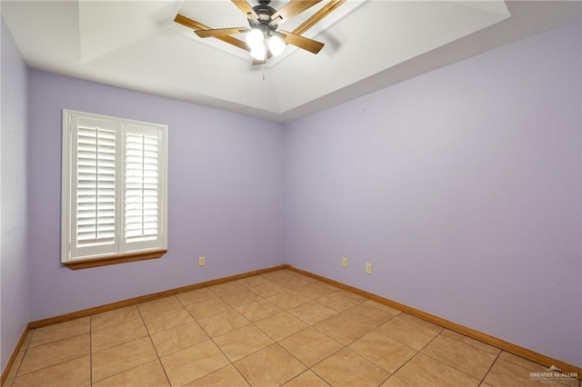 spare room featuring a tray ceiling, ceiling fan, and light tile patterned floors