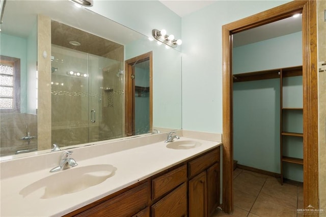 bathroom with a shower with shower door, vanity, and tile patterned floors