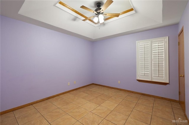 tiled spare room featuring a tray ceiling and ceiling fan