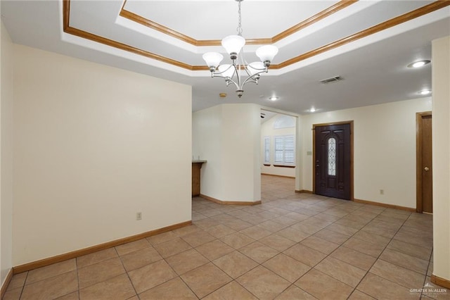 spare room featuring a notable chandelier, a tray ceiling, light tile patterned flooring, and ornamental molding