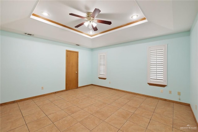 tiled empty room featuring a tray ceiling and ceiling fan