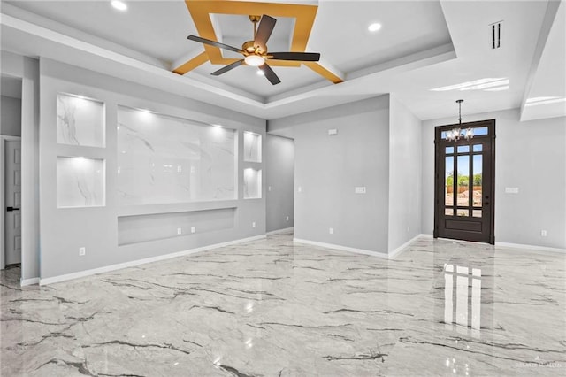 unfurnished living room featuring a raised ceiling and ceiling fan with notable chandelier