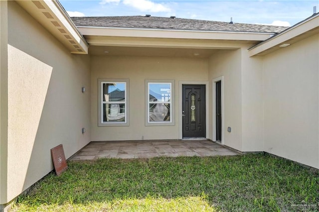 entrance to property featuring a lawn and a patio area