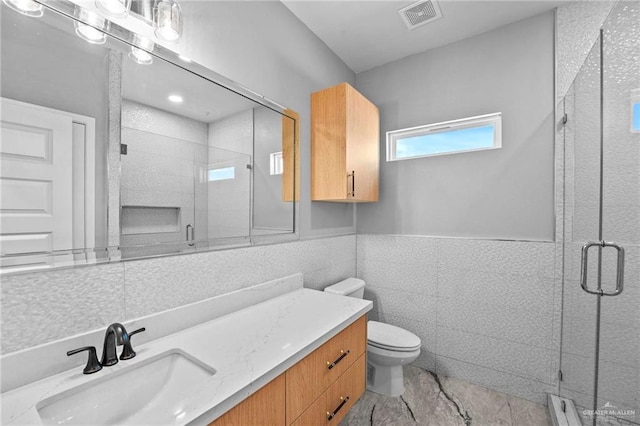 bathroom with vanity, toilet, tile walls, and walk in shower