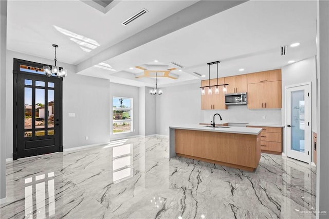 kitchen featuring a kitchen island with sink, sink, pendant lighting, and a notable chandelier