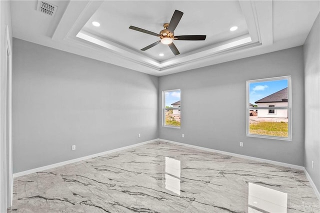 spare room featuring ceiling fan and a raised ceiling