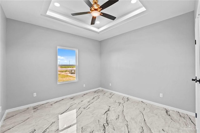 spare room featuring a raised ceiling and ceiling fan