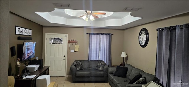 tiled living room featuring ceiling fan and a tray ceiling