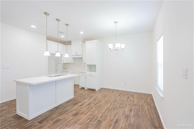 1046 Hidalgo St, Mercedes, TX 78570 - kitchen featuring a sink, wood finished floors, an island with sink, baseboards, and white cabinets