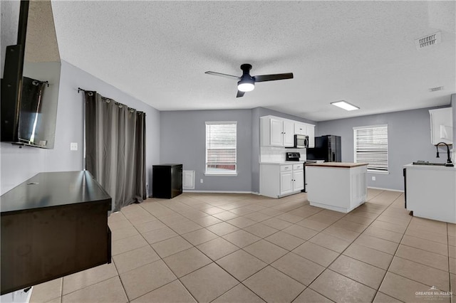 5801 N 36th St, Mcallen, TX 78504 - kitchen featuring black refrigerator with ice dispenser, stainless steel microwave, light tile patterned floors, ceiling fan, and plenty of natural light