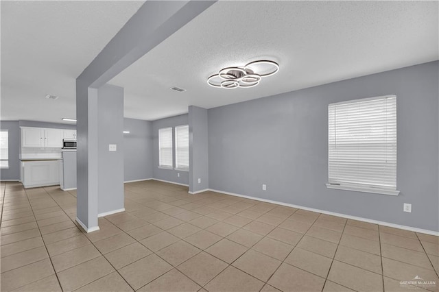 5801 N 36th St, Mcallen, TX 78504 - unfurnished living room with light tile patterned flooring, baseboards, and a textured ceiling