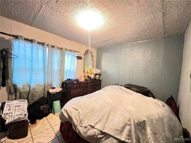 bedroom featuring a textured ceiling, a textured wall, and tile patterned floors