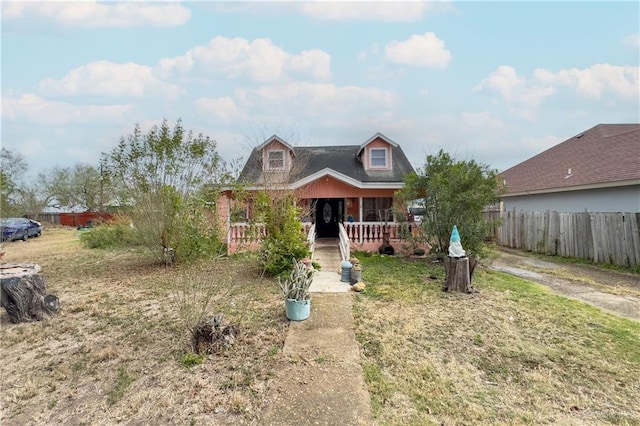 view of front of property featuring a porch, fence, and a front lawn