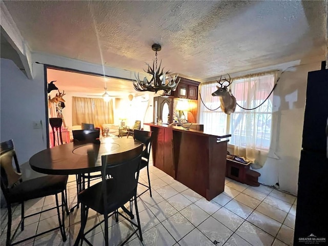 dining room featuring a notable chandelier, a textured ceiling, and light tile patterned flooring