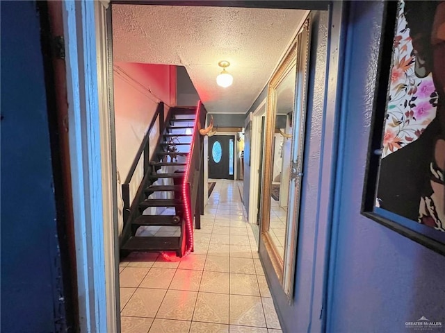 hall with light tile patterned floors, stairway, and a textured ceiling