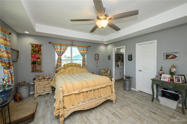 4511 Abbey St, Mercedes, TX 78570 - bedroom featuring a tray ceiling, light wood finished floors, ceiling fan, ensuite bathroom, and baseboards