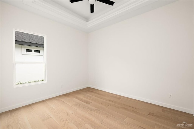 unfurnished room with a tray ceiling, ceiling fan, crown molding, and light wood-type flooring