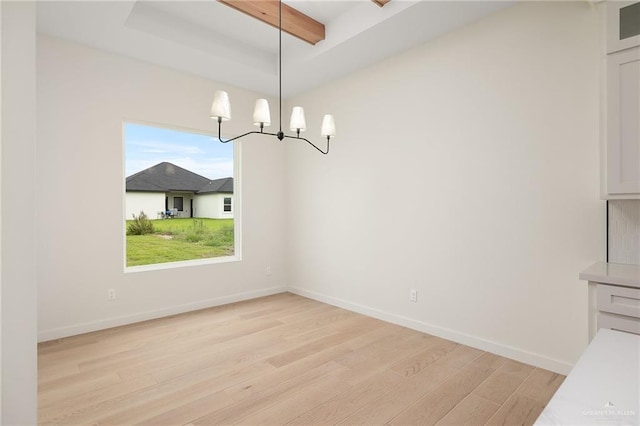 unfurnished dining area featuring a chandelier, beamed ceiling, and light hardwood / wood-style floors