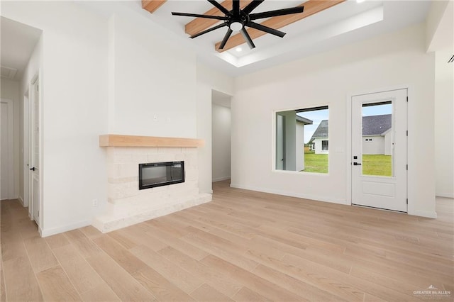 unfurnished living room with a tray ceiling, light hardwood / wood-style flooring, and ceiling fan