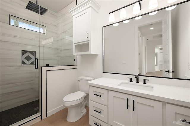 bathroom with hardwood / wood-style floors, vanity, toilet, and a shower with shower door