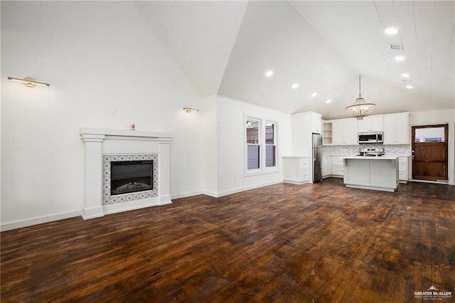 unfurnished living room with dark hardwood / wood-style flooring, vaulted ceiling, and a tile fireplace