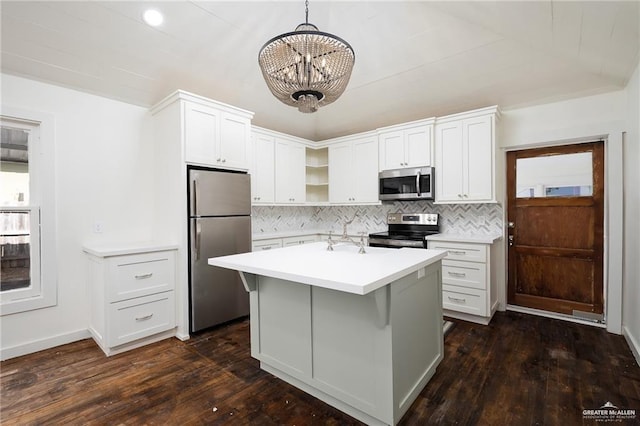 kitchen featuring stainless steel appliances, white cabinetry, dark wood-type flooring, and decorative light fixtures